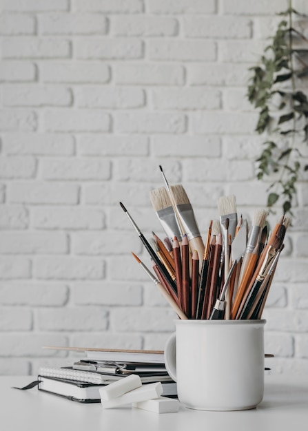 Arrangement with pens and brushes in cup