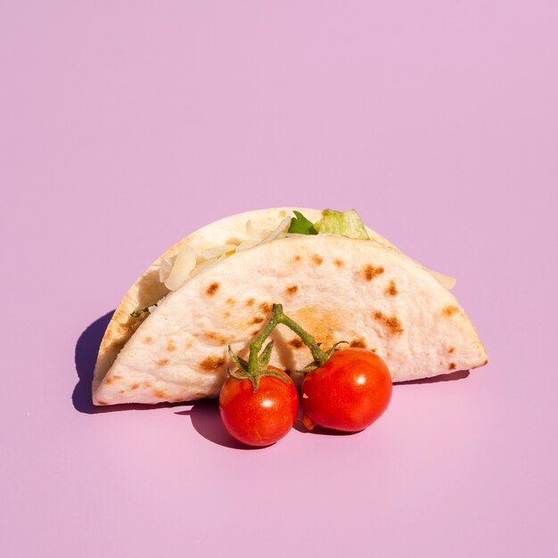 Arrangement with taco and cherry tomatoes on purple background