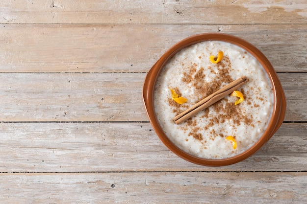 Arroz con leche Rice pudding with cinnamon in clay bowl on wooden table