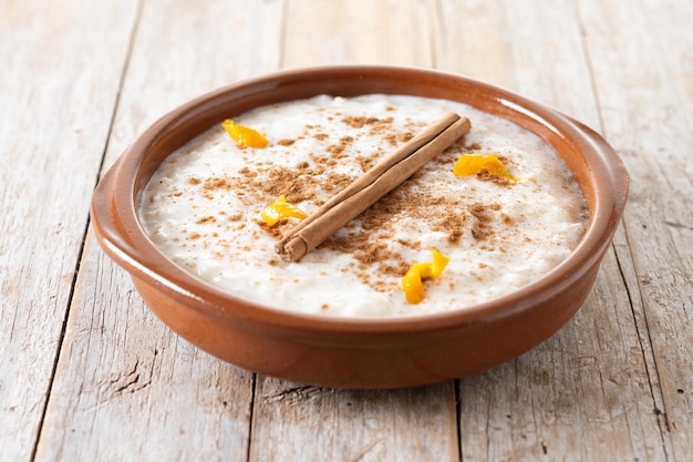 Free Photo arroz con leche rice pudding with cinnamon in clay bowl on wooden table