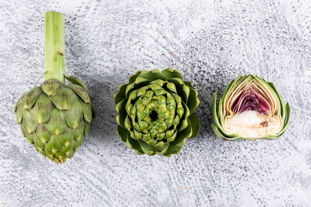 Artichokes and a slice on a light gray . top view.