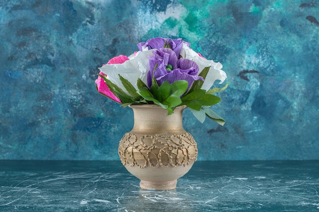 Artificial colorful flower in a vase , on the blue background.