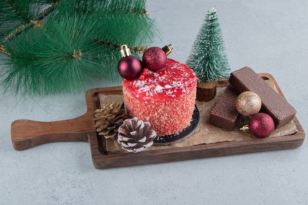 Artificial pine branch next to a tray of assorted desserts on marble background.