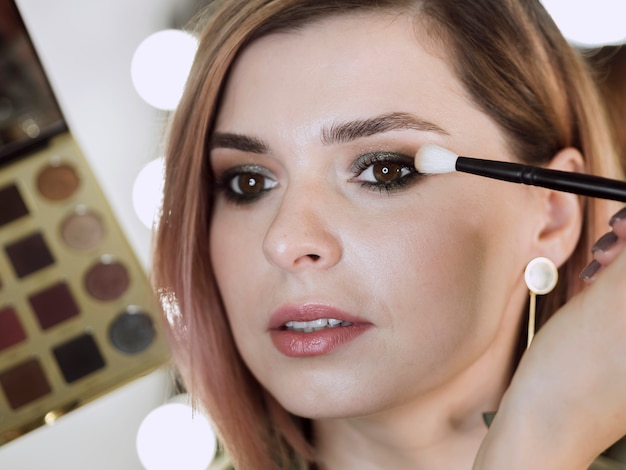 Artist applying make-up on beautiful woman