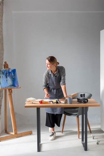 Free photo artist in apron working on desk