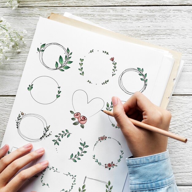 Artist drawing doodle floral wreaths on a paper