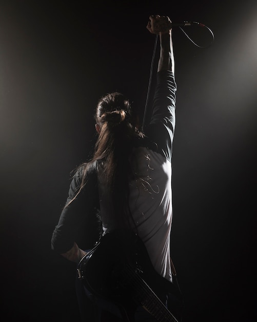 Artist holding a microphone on stage from the back