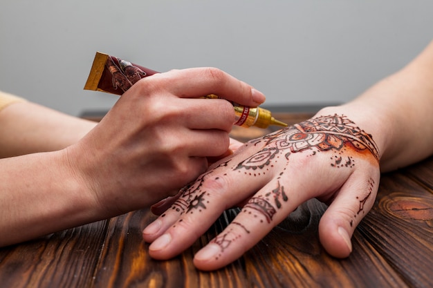 Artist making mehndi on womans hand on table