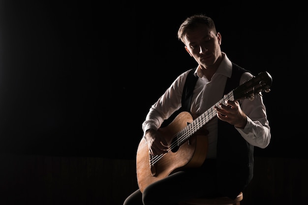 Artist man on stage playing the classical guitar copy space