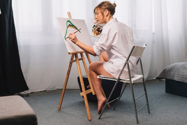 Free photo artist painting sitting on chair