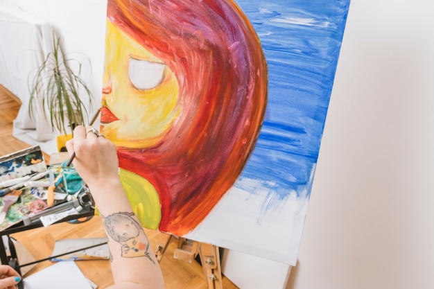 Free photo artist painting woman on easel in workshop