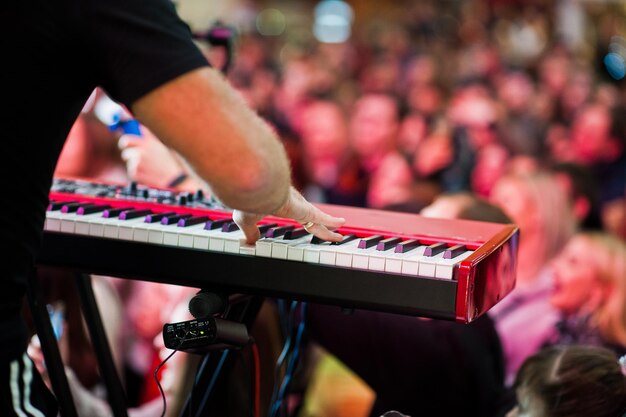 Artist play on audio piano on stage in a concert hall behing peoples