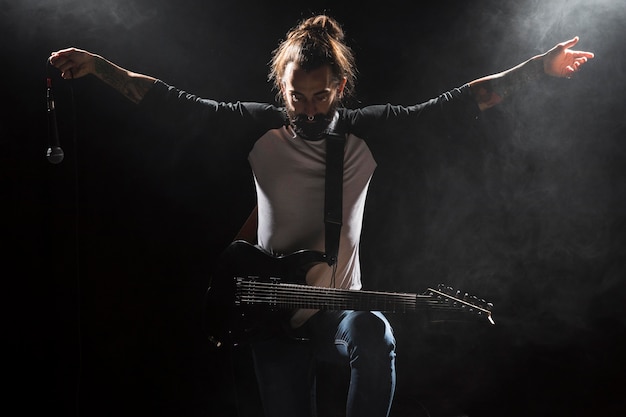 Free photo artist playing guitar and holding a microphone