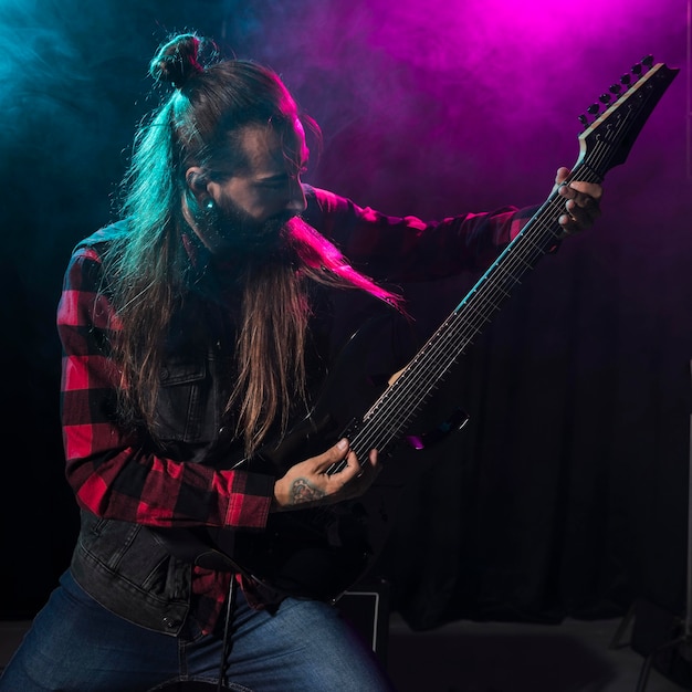 Artist playing guitar and looking at the instrument