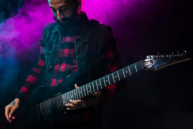 Free photo artist playing guitar and violet stage light and smoke