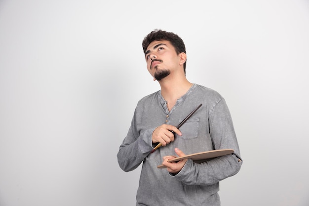 Artist putting his brush up to his head and thinking about creative ideas.