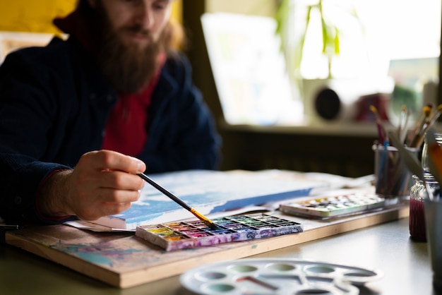 Free photo artist using watercolor to paint his art in the studio