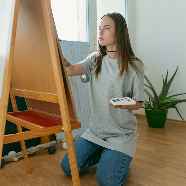 Free photo artist woman painting on canvas  side view