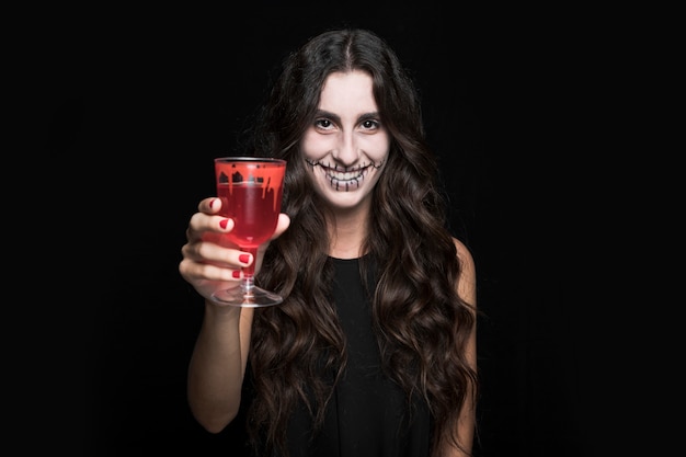 Ashy woman showing glass with red liquid