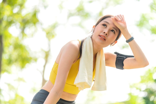 Free Photo asian active female runner workout standing bent over and catching her breath after a running session in the park garden sports female woman taking break after a run in morning exercise lifestyle