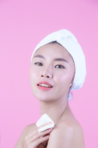 Asian beautiful woman wiping the face on a pink background, Cosmetology and Spa .