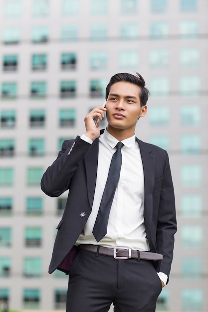 Free photo asian business man calling on phone outside