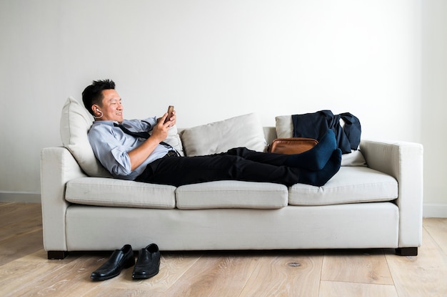 Free photo asian businessman taking break laying on couch