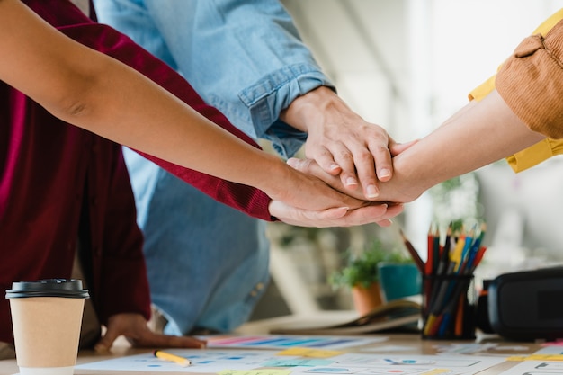 Free Photo asian businessmen and businesswomen meeting brainstorming putting hands up for new startup and giving strength motivation working together in modern creative office. coworker teamwork concept.