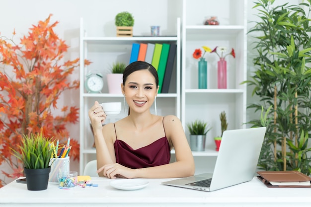 Asian businesswoman take a coffee break after working at laptop computer on desk