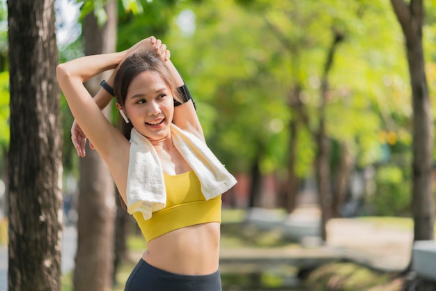 Asian cheerful young adult Attractive and strong morning stretching before runin the park Sports concept Healthy lifestyle Young fitness woman runner stretching before run on The park