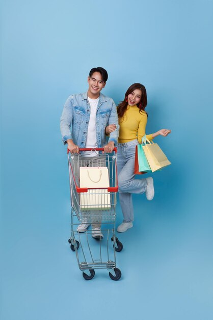 Asian couple have fun drive shopping trolley cart and holding shopping bag in supermaeket