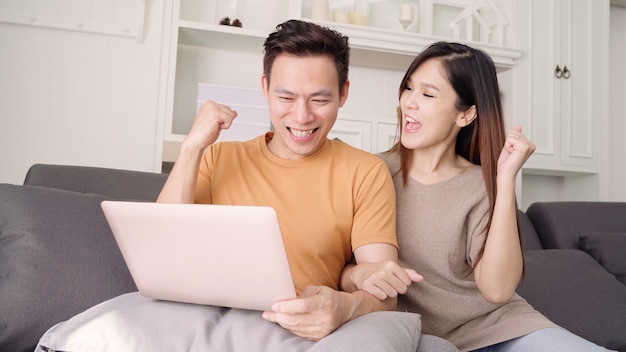 Asian couple using laptop for search web in living room at home