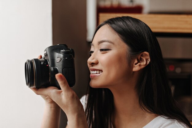 Asian dark-haired woman with smile makes photo on black front