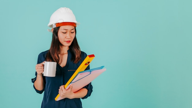 Free photo asian draftswoman with mug looking at plans