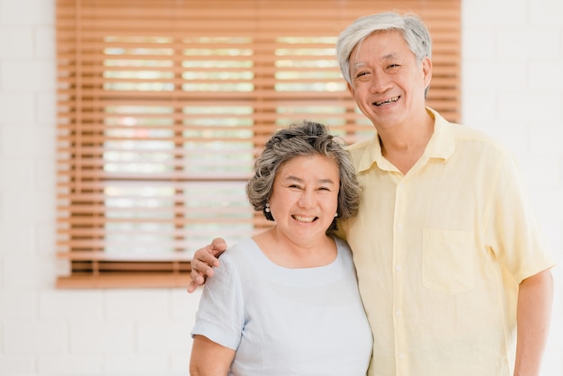 Asian elderly couple feeling happy smiling and looking to camera while relax in living room at home. 