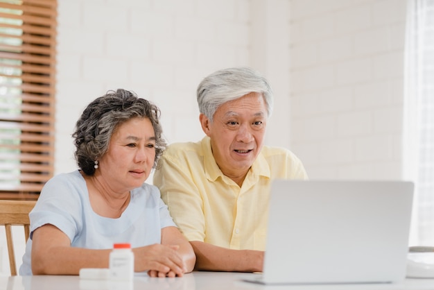 Asian elderly couple using laptop conference with doctor about medicine information in living room