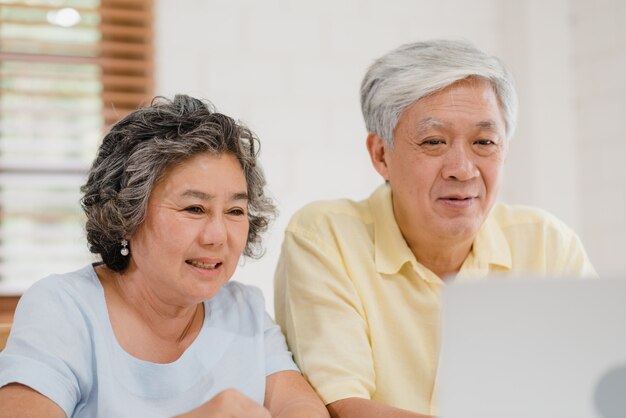 Asian elderly couple using laptop conference with doctor about medicine information in living room