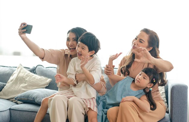 Asian family happy using smartphone taking a selfie photo together in the living room