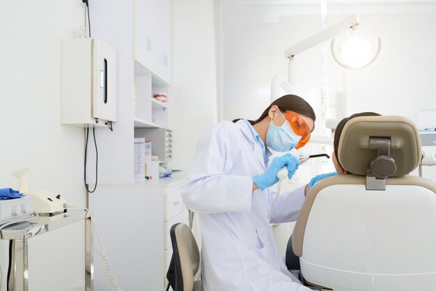 Asian female dentist treating patient's cavity in clinic