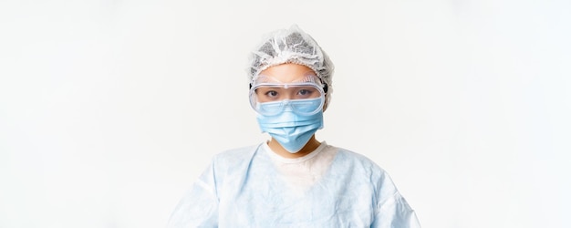 Free photo asian female doctor or nurse wearing personal protective equipment with face medical mask and protective glasses standing over white background