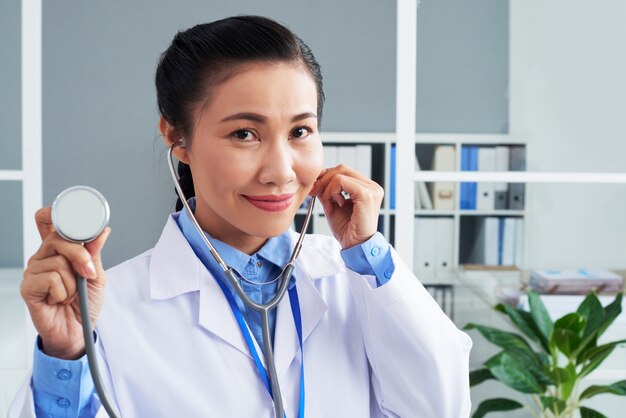 Asian female doctor posing with stethoscope in clinic