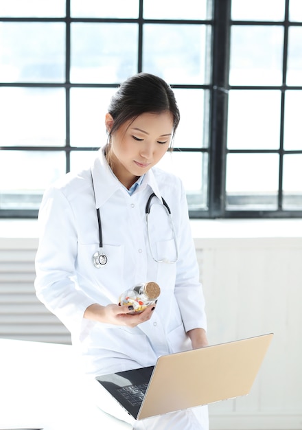 Asian female doctor, woman specialist with laptop and pills