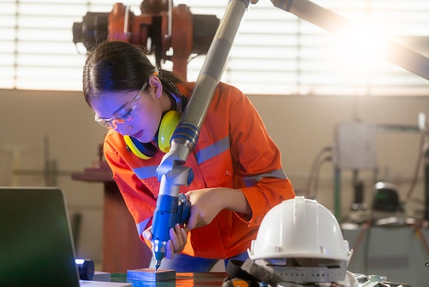 Asian female engineer specialist with Measuring machine with a manipulator armThreedimensional coordinate measurement Check sizes 3D check of the sizes of parts CMM after machining process