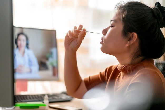 Asian female hand nasal swab testing rapid tests by herself for detection of the SARS co2 virus by tele video doctor instruction at home isolate quarantine concept