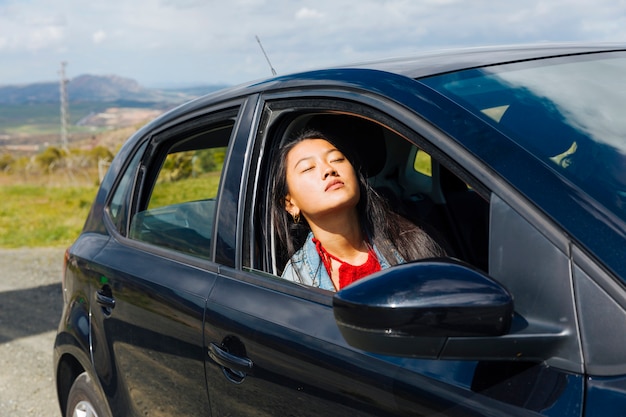 Asian female sitting in car and enjoying sun 