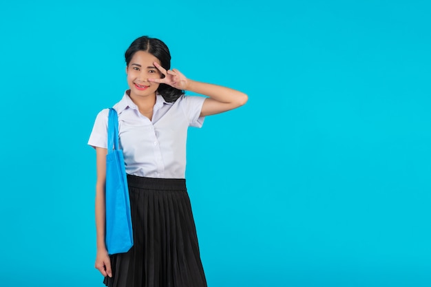 An Asian female student who spins a cloth bag and shows various gestures on a blue .