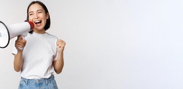 Asian girl shouting at megaphone young activist protesting using loud speakerphone making announceme