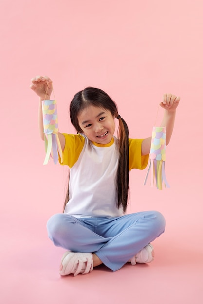 Free photo asian girl showing paper fishes