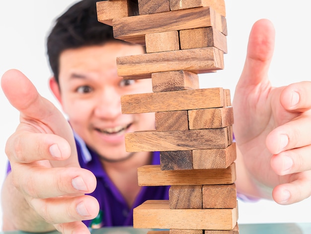 Free photo asian guy is playing jenga, a wood blocks tower game