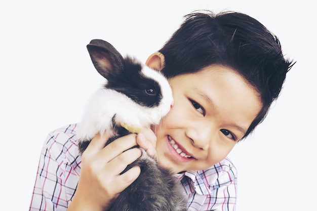 Free Photo asian kid playing with lovely baby rabbit isolated over white